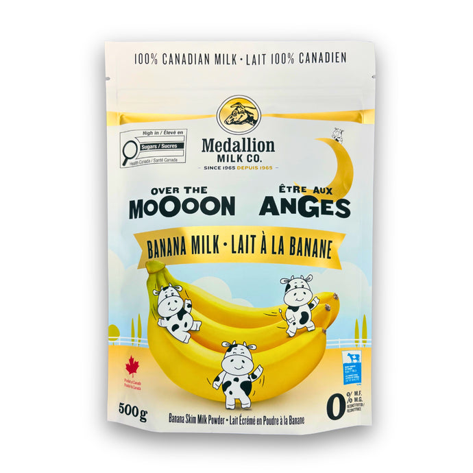 Medallion Milk Co. Banana Milk 500 g pouch featuring playful cartoon cows sitting on bananas under a crescent moon. The packaging highlights “Over the Moooon,” “100% Canadian Milk,” and “Banana Skim Milk Powder.” Product of Canada with a bright yellow and blue design.