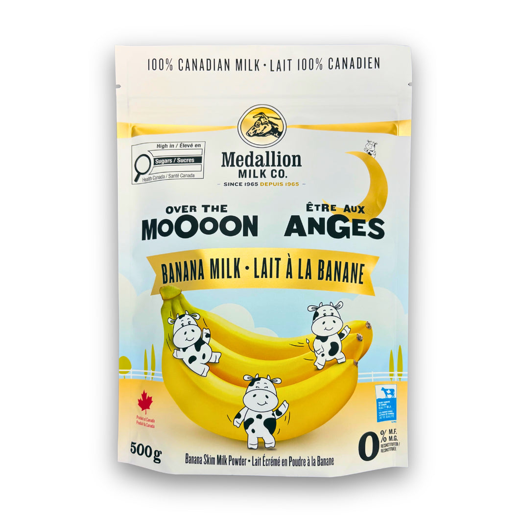 Medallion Milk Co. Banana Milk 500 g pouch featuring playful cartoon cows sitting on bananas under a crescent moon. The packaging highlights “Over the Moooon,” “100% Canadian Milk,” and “Banana Skim Milk Powder.” Product of Canada with a bright yellow and blue design.